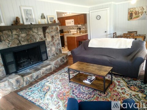 A living room with a stone fireplace and a grey couch.