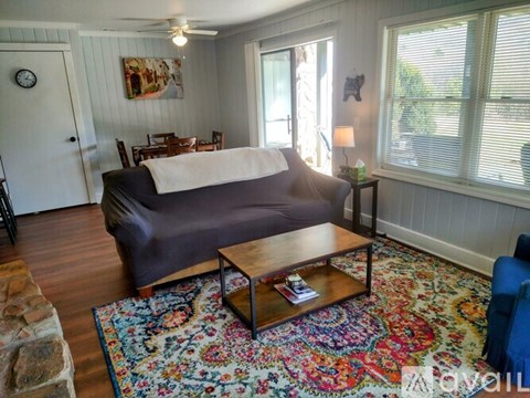 A living room with a grey couch, a wooden coffee table, and a colorful rug.