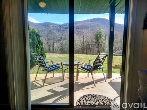 A patio with chairs and a table overlooks a mountainous landscape.
