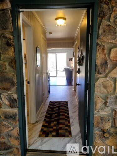 A hallway with a stone wall and a checkered floor mat.