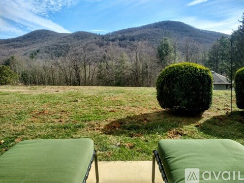 Two green chairs are in the foreground of a mountainous landscape.