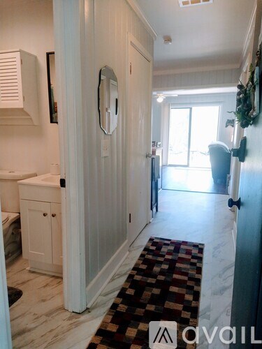 A hallway with a rug on the floor and a door on the right.