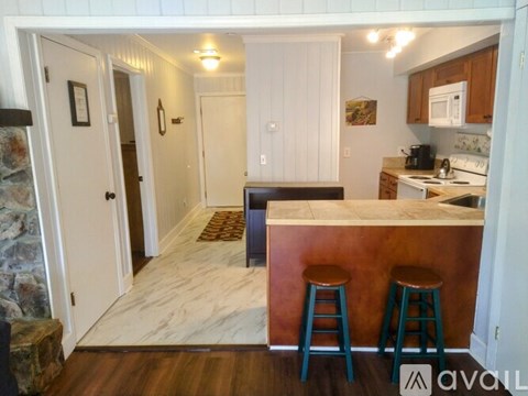 A kitchen with a bar stool in front of a counter.