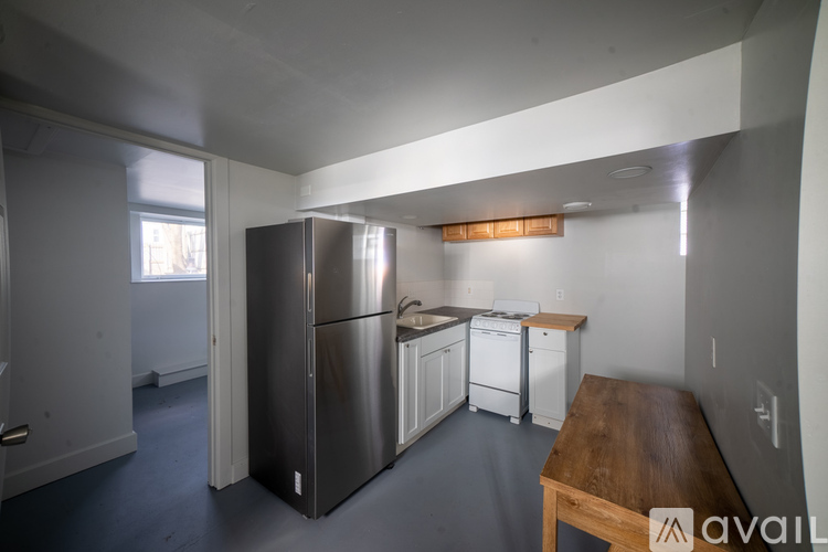 A kitchen with a refrigerator, sink, and cabinets.
