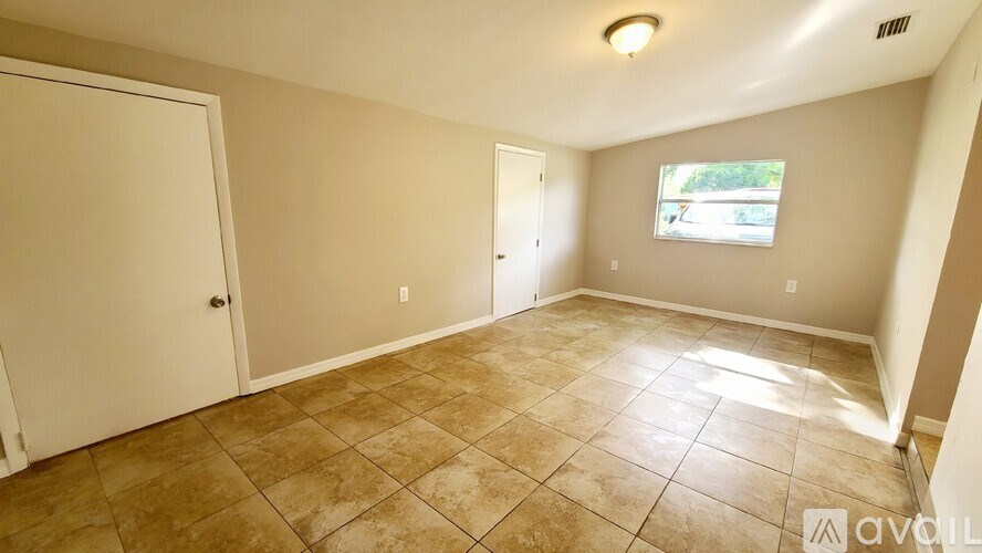 A room with beige walls and a tiled floor with a window showing a view of a street.