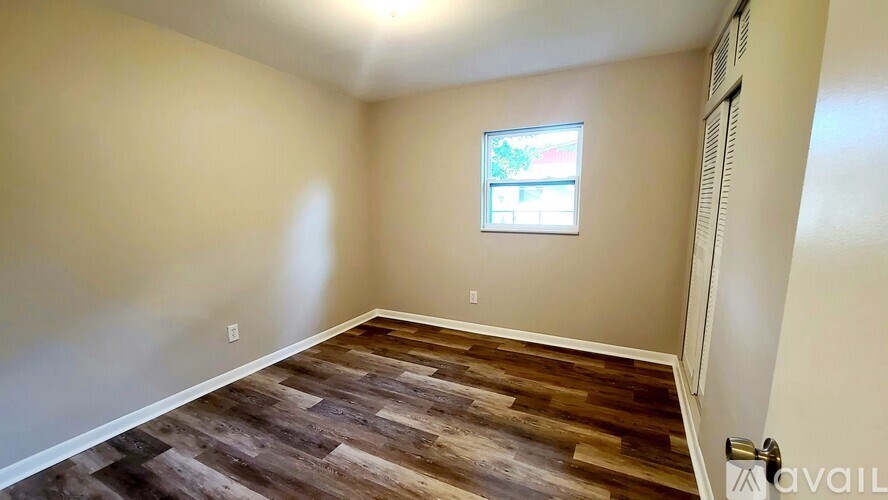 A room with wooden flooring and a window.