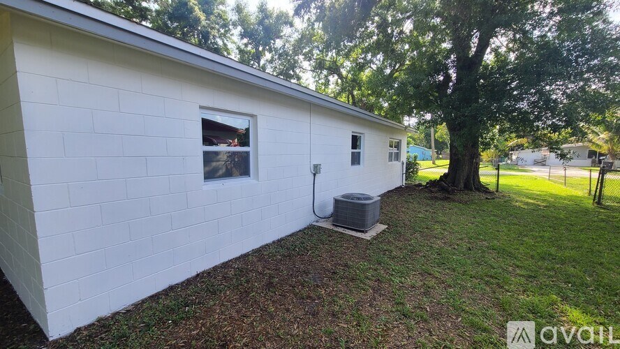 A white house with a window and a tree in front.