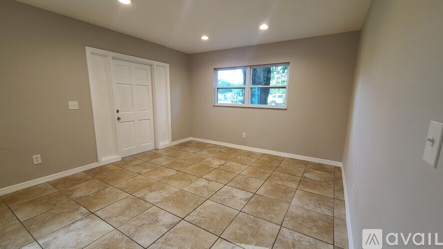 A room with beige tiled flooring and a window with a view of trees.