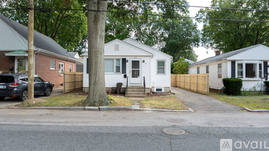 A black car is parked in front of a red brick house.
