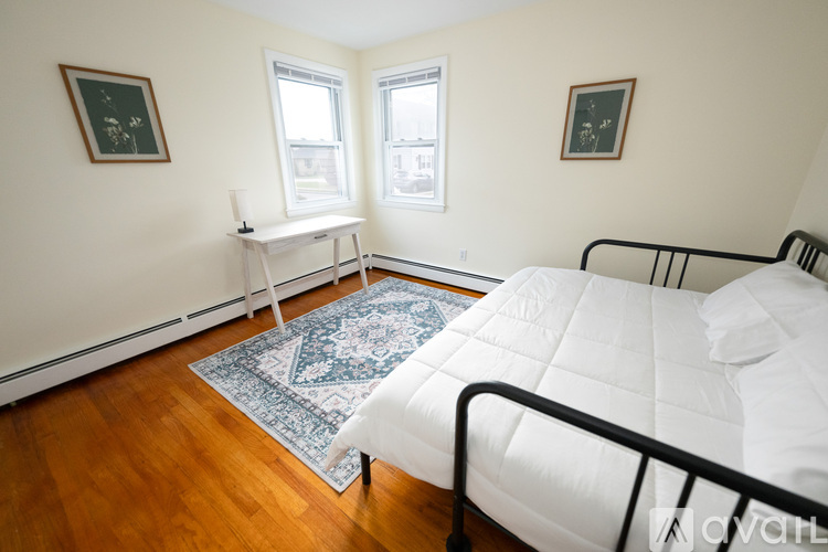 A bedroom with a white bed and a blue rug.