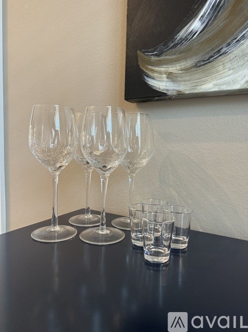 A row of wine glasses and shot glasses are lined up on a table.