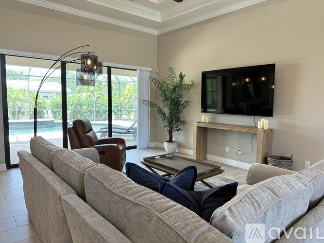 A living room with a grey couch, a television, and a plant.
