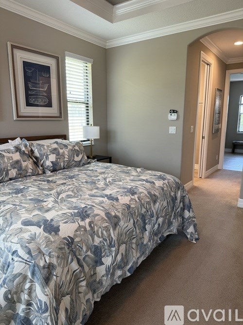 A bedroom with a large bed and a painting on the wall.