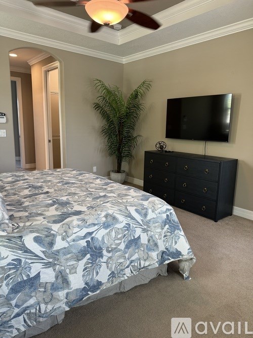 A bedroom with a bed, dresser, and a ceiling fan.