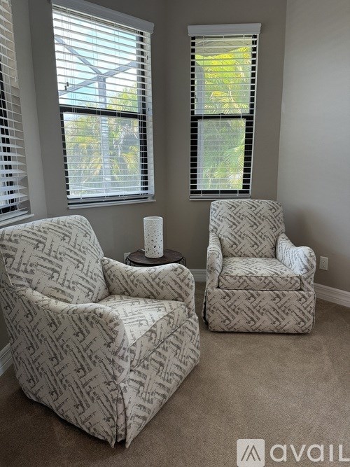 Two chairs with patterned upholstery are placed in a room with a window.
