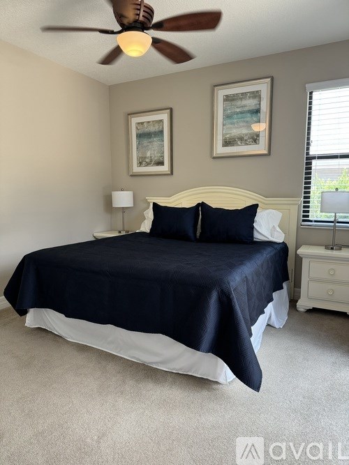 A bedroom with a bed, nightstand, and a ceiling fan.