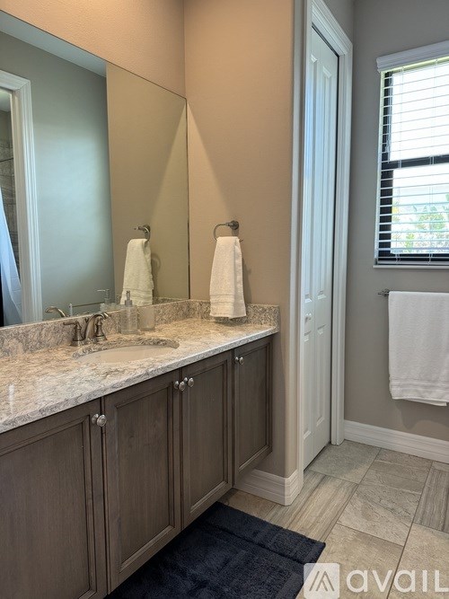 A bathroom with a marble countertop and wooden cabinets.