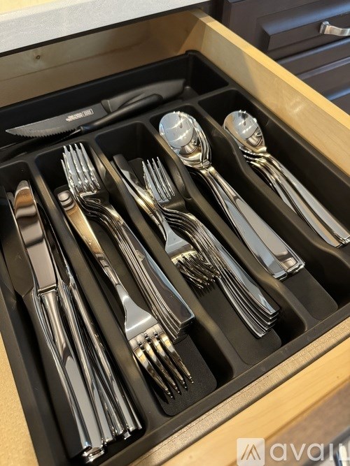 A set of silverware is neatly arranged in a black tray.