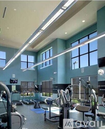 A gym with various exercise equipment and a flat screen TV mounted on the wall.