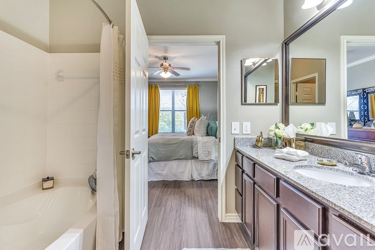 A bathroom with a white tub and a bedroom with a bed and a window.