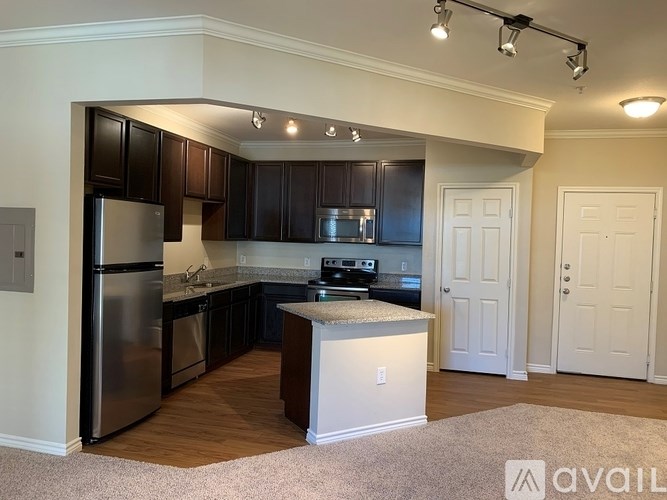 A kitchen with dark brown cabinets and a stainless steel refrigerator.