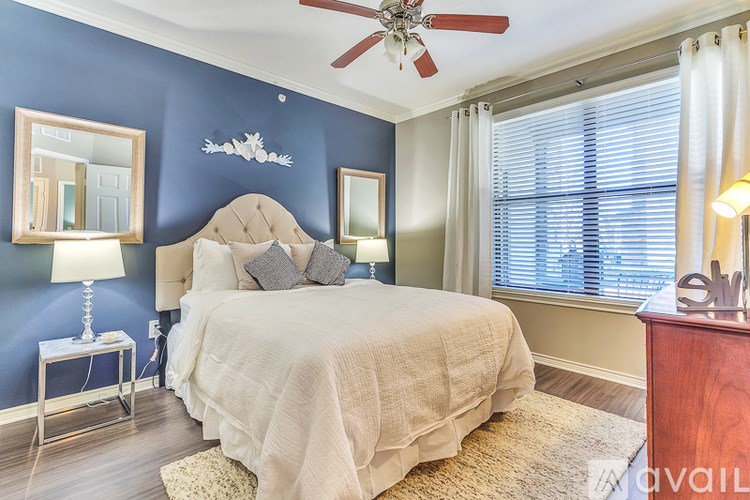 A bedroom with a bed, a ceiling fan, and a window with blinds.