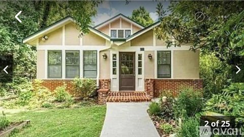 A house with a brown door and a brick pillar.