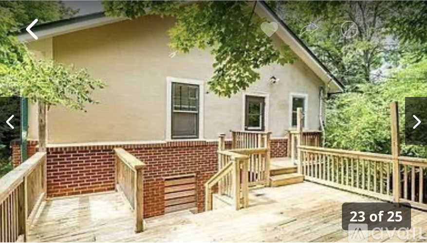 A house with a deck and a tree in front.
