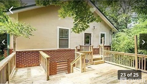 A house with a deck and a tree in front.