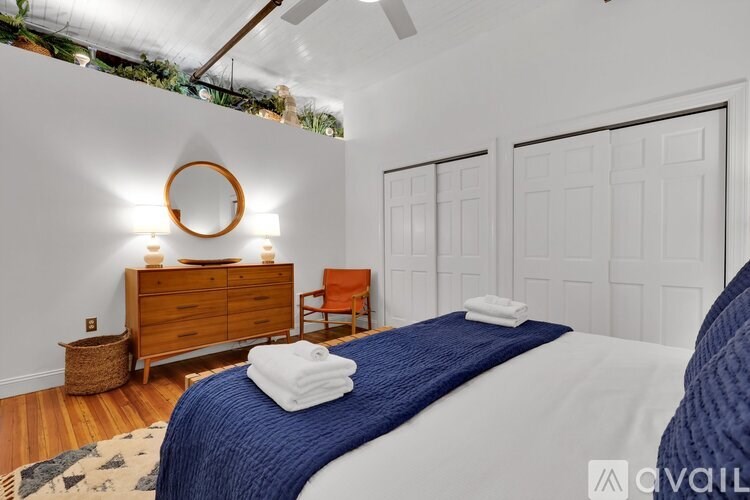 A bedroom with a bed, a dresser, and a chair.