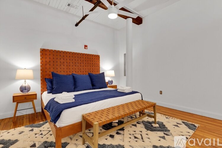 A bedroom with a bed, a bench, and a ceiling fan.