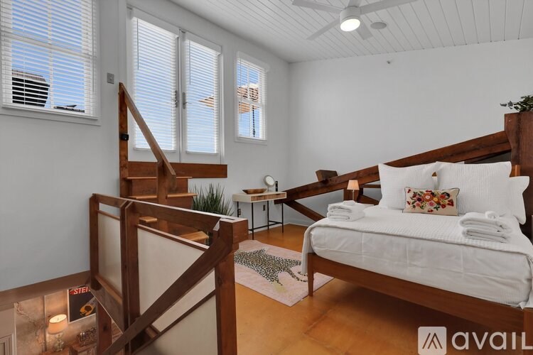 A bedroom with a bed, a staircase, and a ceiling fan.