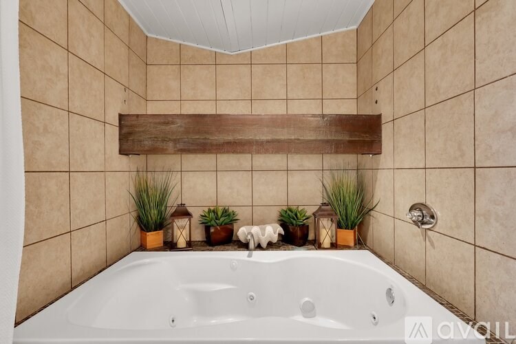 A bathroom with a white tub and a wooden shelf above it.