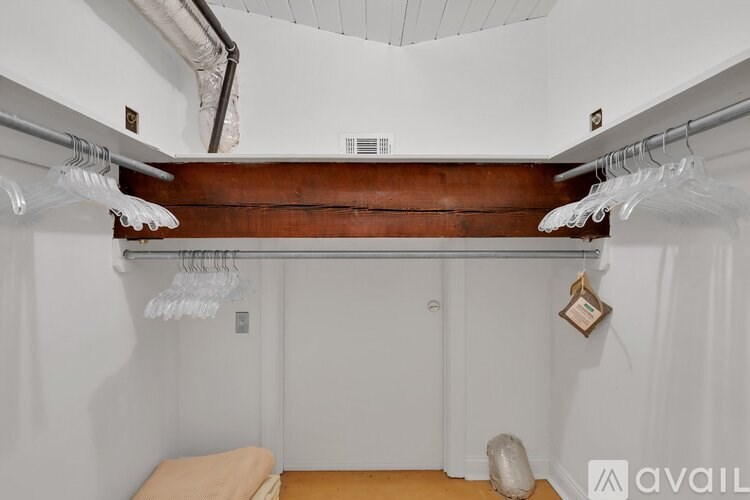A walk-in closet with a wooden shelf and white hangers.