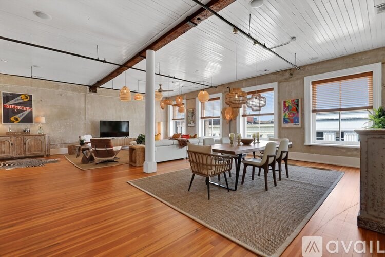 A living room with a wooden floor and a dining table with chairs.