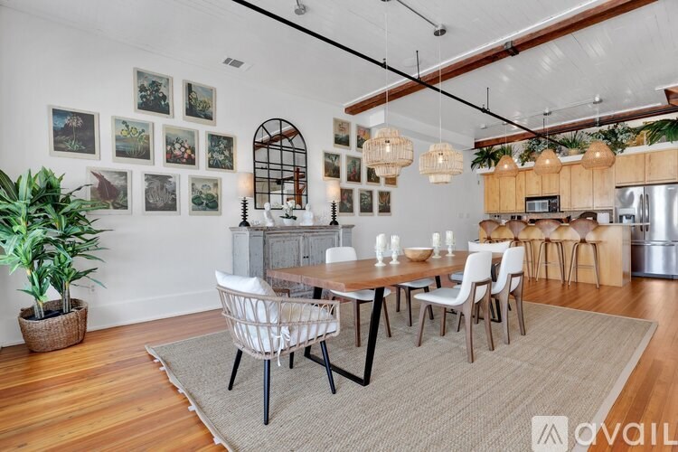 A dining room with a wooden table and chairs, a potted plant, and pictures on the wall.