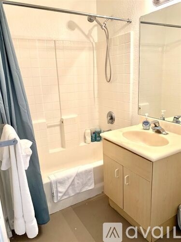 A bathroom with a white sink and a shower with a curtain.