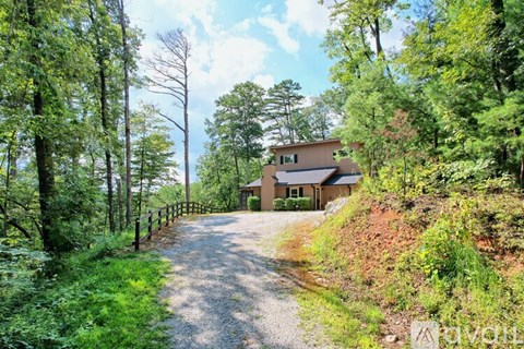 A house is situated on a hill with a gravel road leading to it.