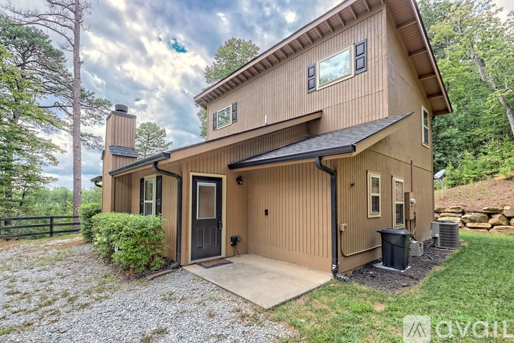 A house with a brown exterior and a black door is surrounded by trees.