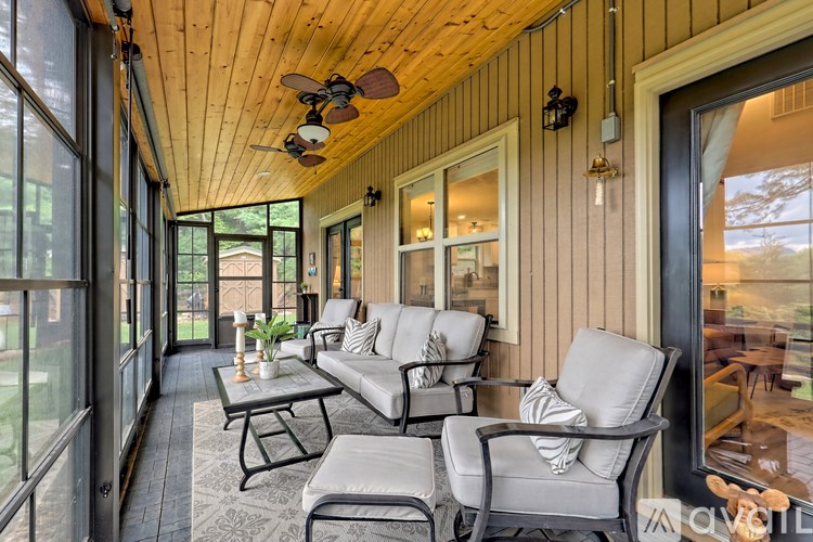 A sunroom with a wooden ceiling and a glass door leading to a backyard.