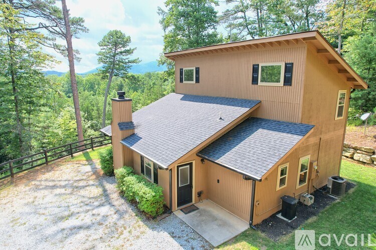 A house with a brown exterior and a grey roof is surrounded by trees.
