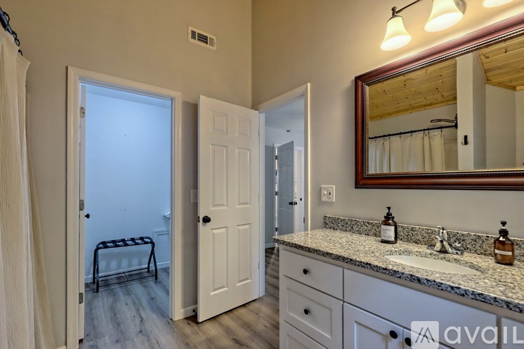 A bathroom with a white door, a mirror, and a sink.
