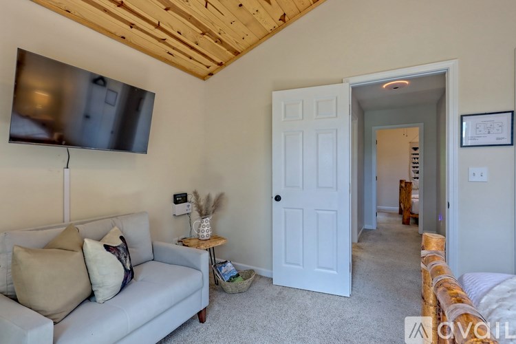 A living room with a couch, a small table, and a flat screen TV mounted on the wall.