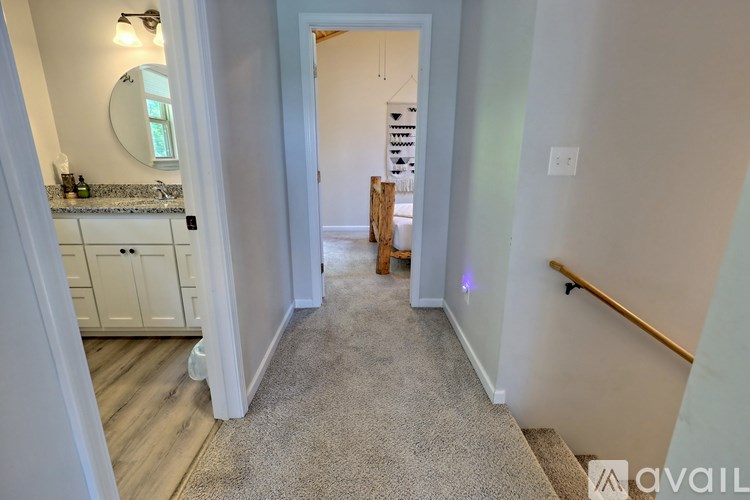 A hallway with a carpeted floor and a wooden staircase.