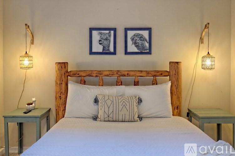A bedroom with a bed, two lamps, and two framed pictures on the wall.