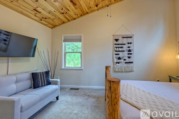 A bedroom with a bed, couch, and window.