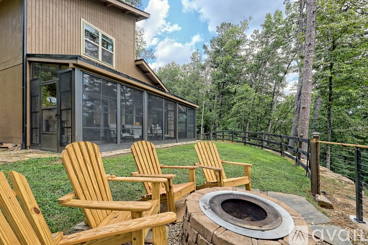 Three wooden chairs are placed in front of a fire pit on a patio.