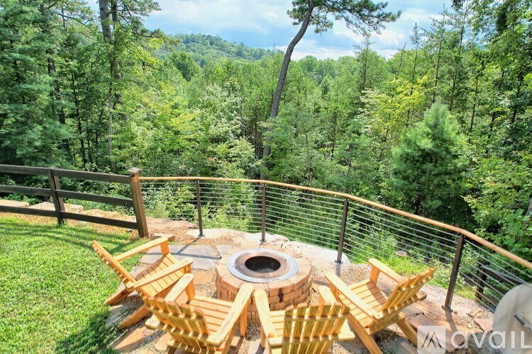 A wooden table and chairs are set up on a deck overlooking a forest.