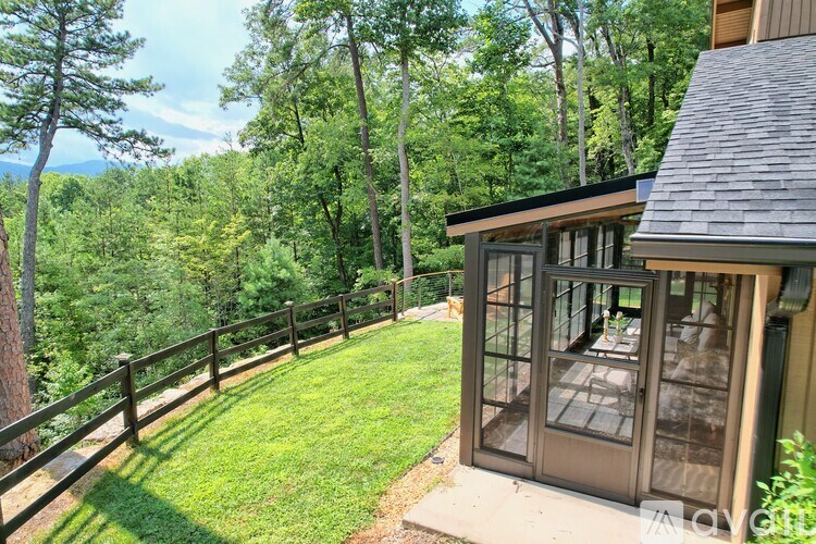 A house with a glass door and a wooden fence in front of a forest.