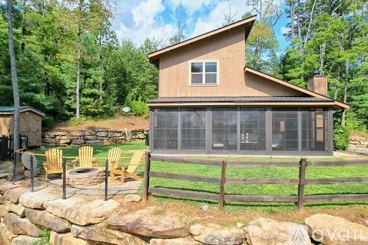 A house with a stone wall and a fence in front of it.